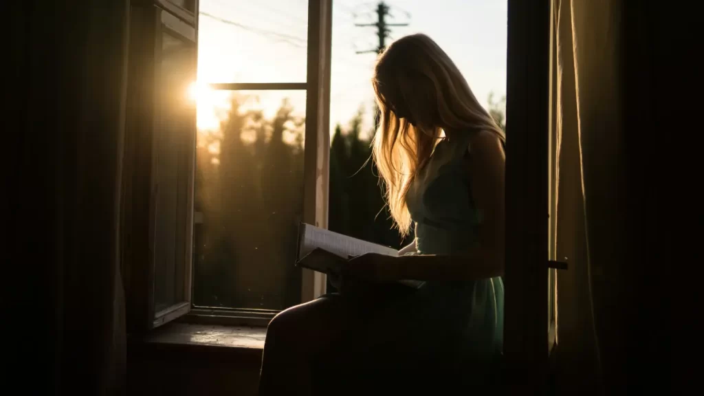 girl-reading-book-beside-window